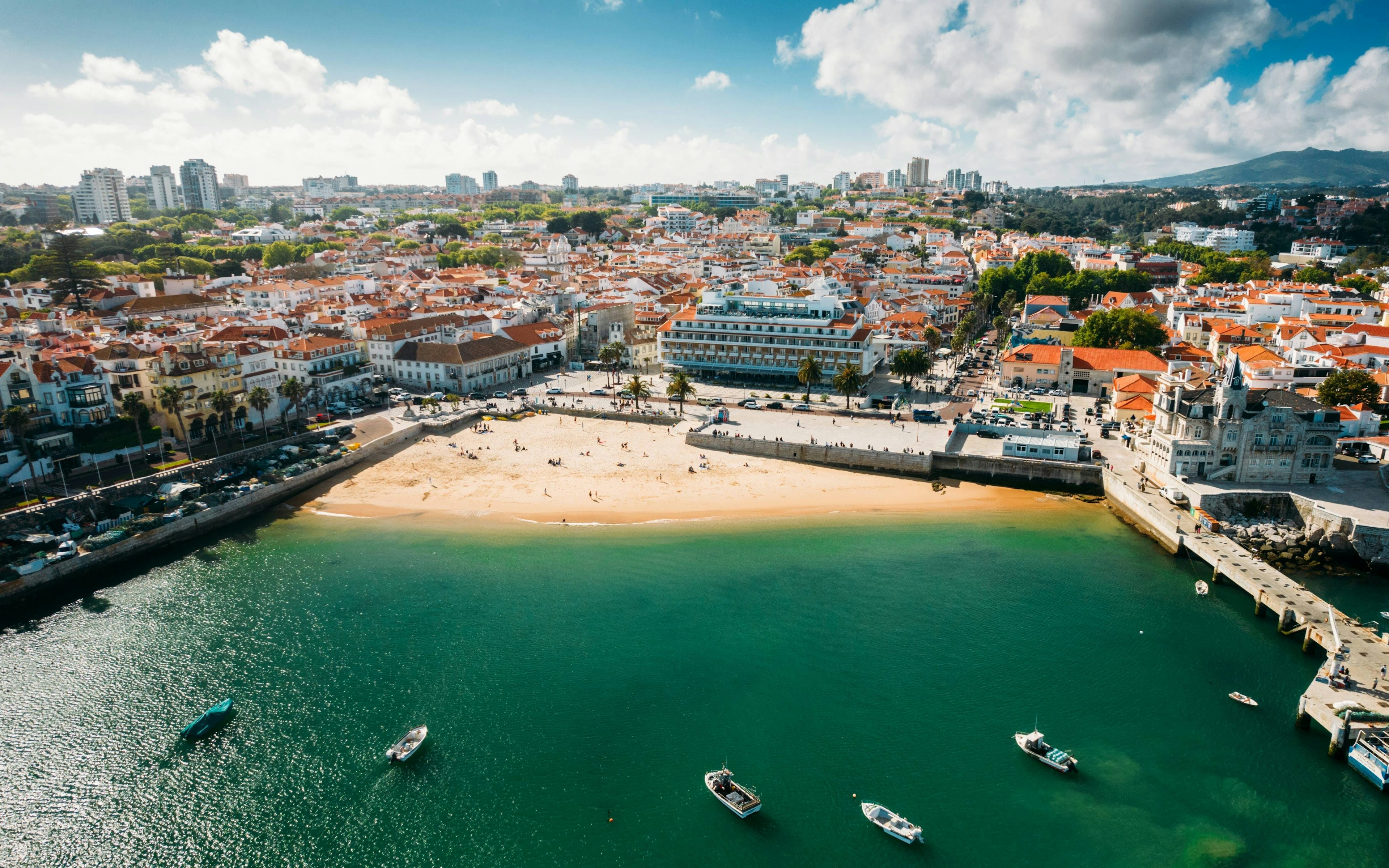 View of Cascais bay with clear green waters, overlooking the City Hall and Baía Hotel buildings.