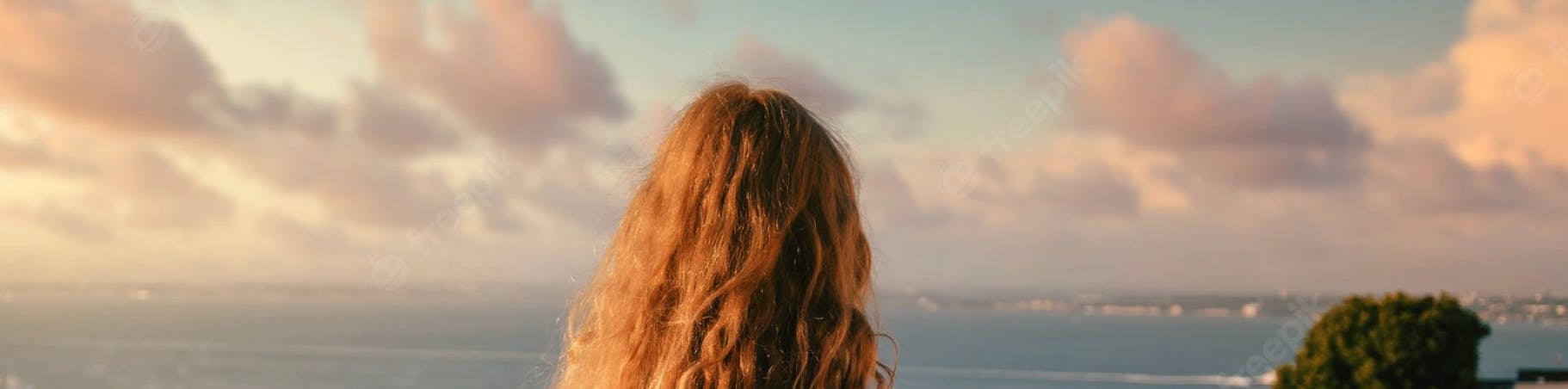 Mulher ruiva de costas olhando para o oceano