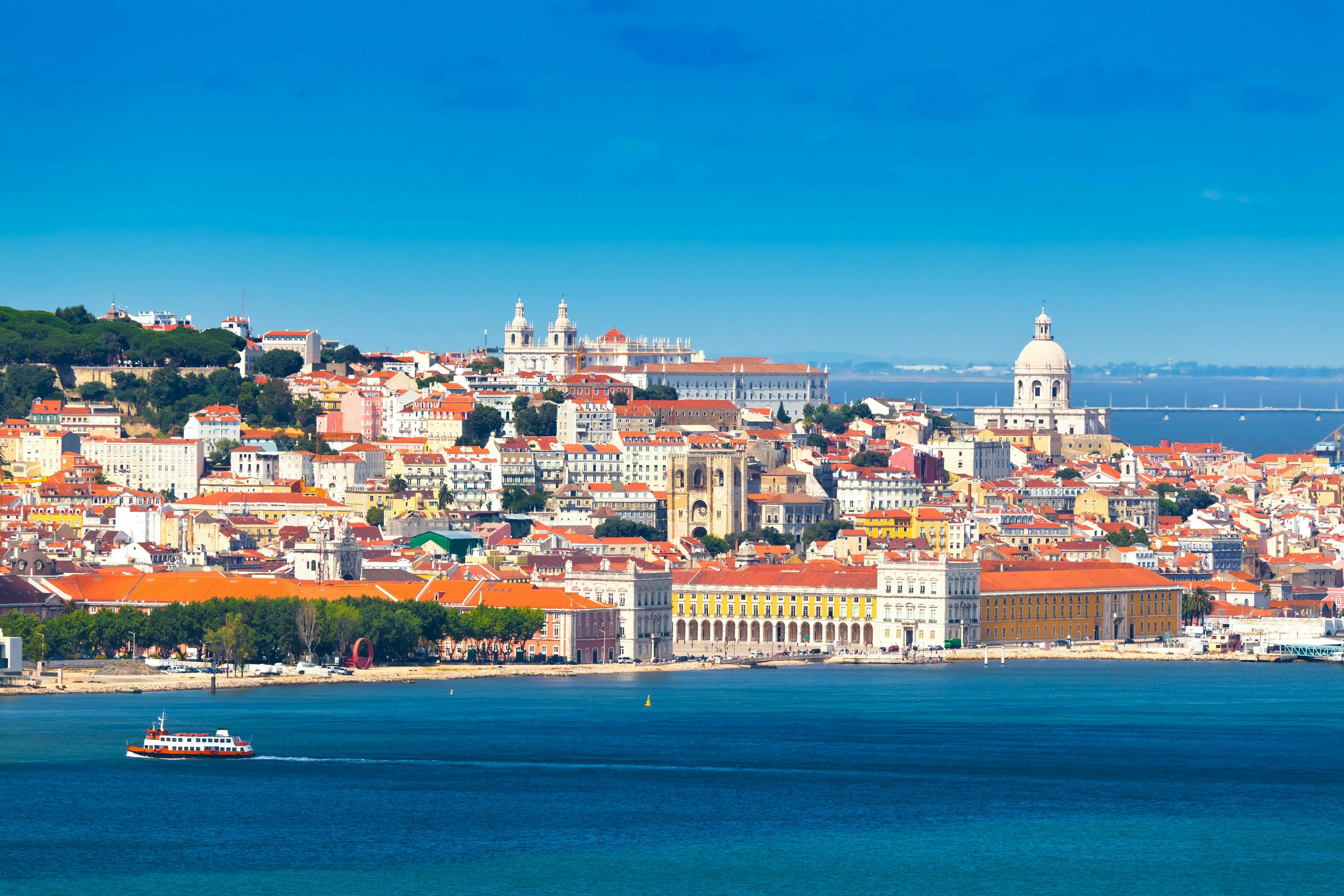 Uma vista panorâmica de Lisboa com o Rio Tejo e a Ponte Vasco da Gama ao fundo, ligando Lisboa à Margem Sul.