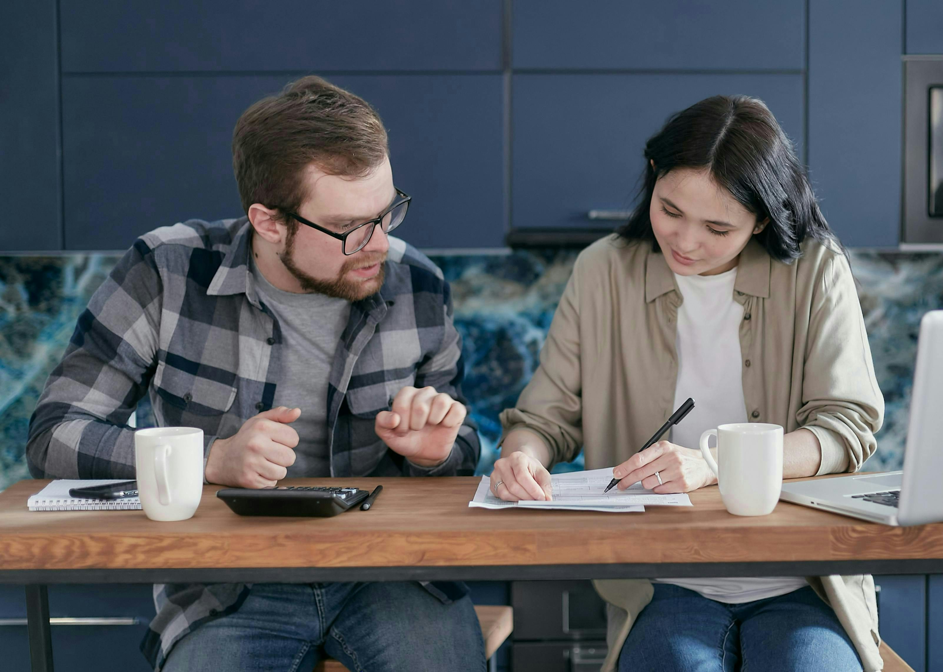 Man and woman sitting together, reviewing and discussing their tax documents spread out on a table.