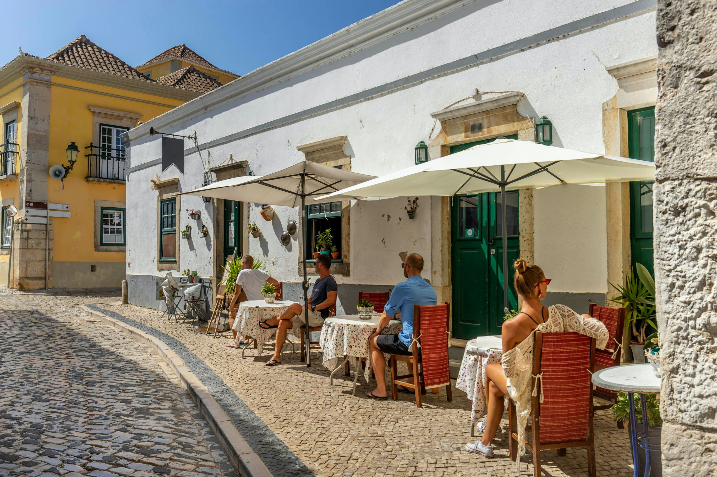 A photo of people sitting outside a cafe beside the street in Portugal
